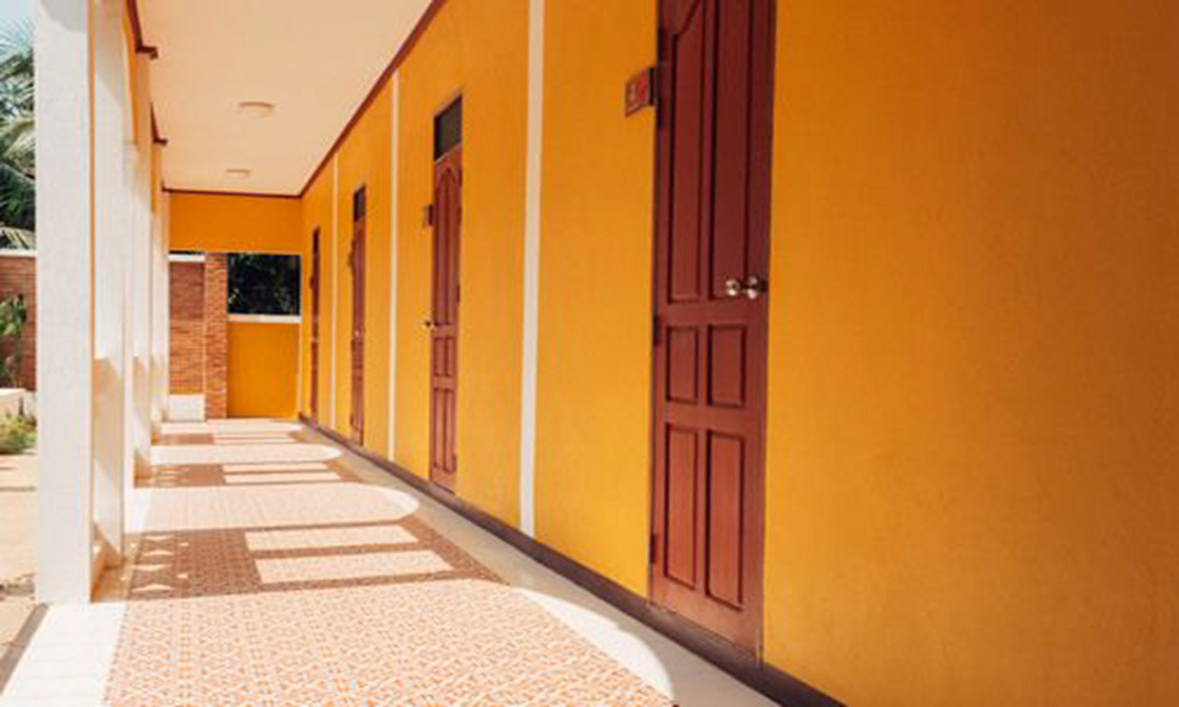 A corridor with yellow walls and wooden doors.