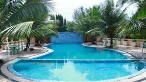 A swimming pool with a tiled edge, surrounded by palm trees and a patterned floor. - Om Leisure Resort Puri (Brahmagiri)