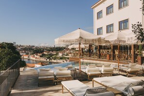 Enjoy breathtaking views of the city and river from our rooftop pool area, featuring lounge chairs and umbrellas.