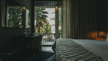 A hotel room with a bed, desk, and a balcony with a view of palm trees.