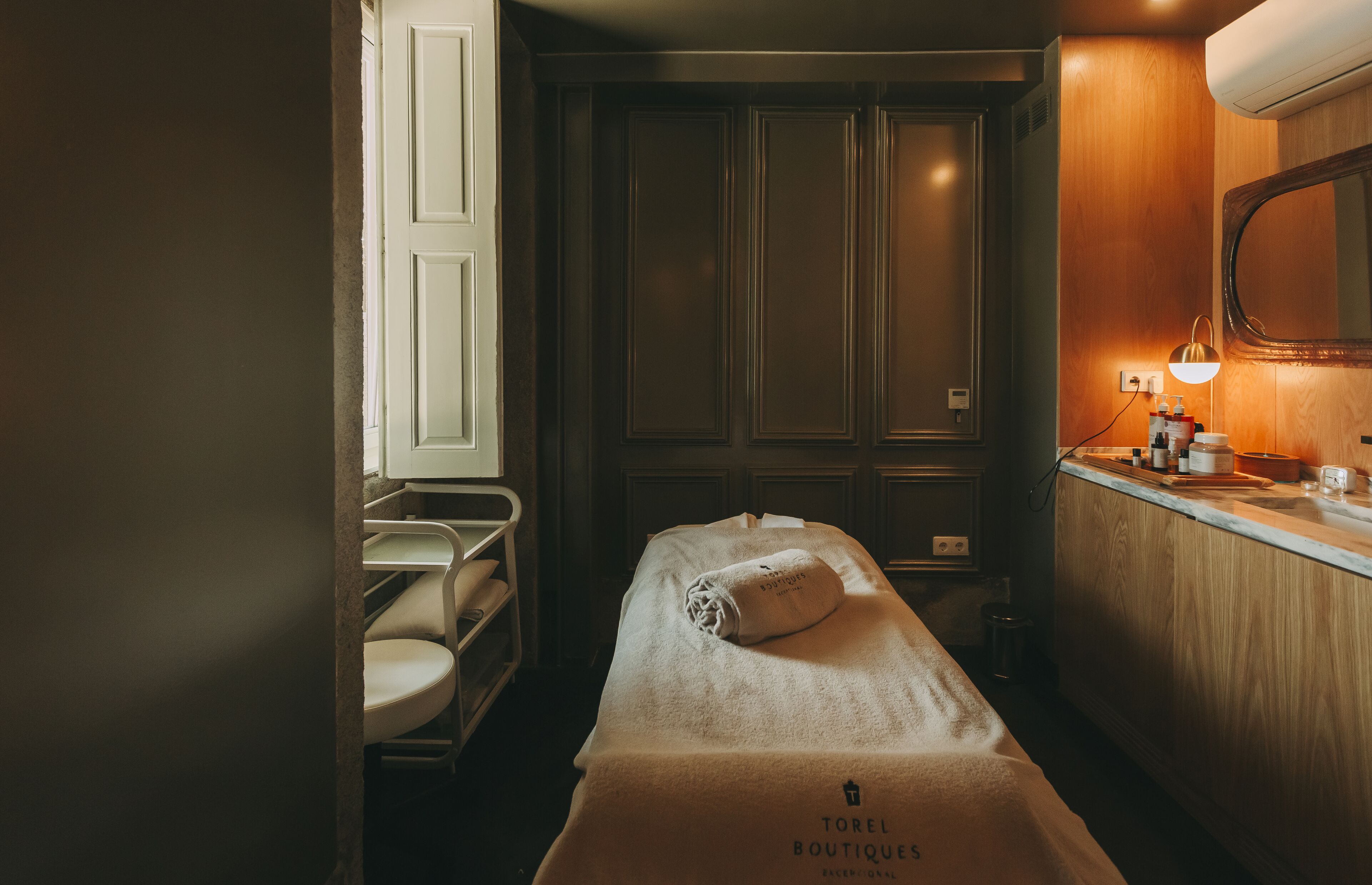 Una habitación de hotel con cama, una mesita con artículos de aseo, un espejo y una ventana.
