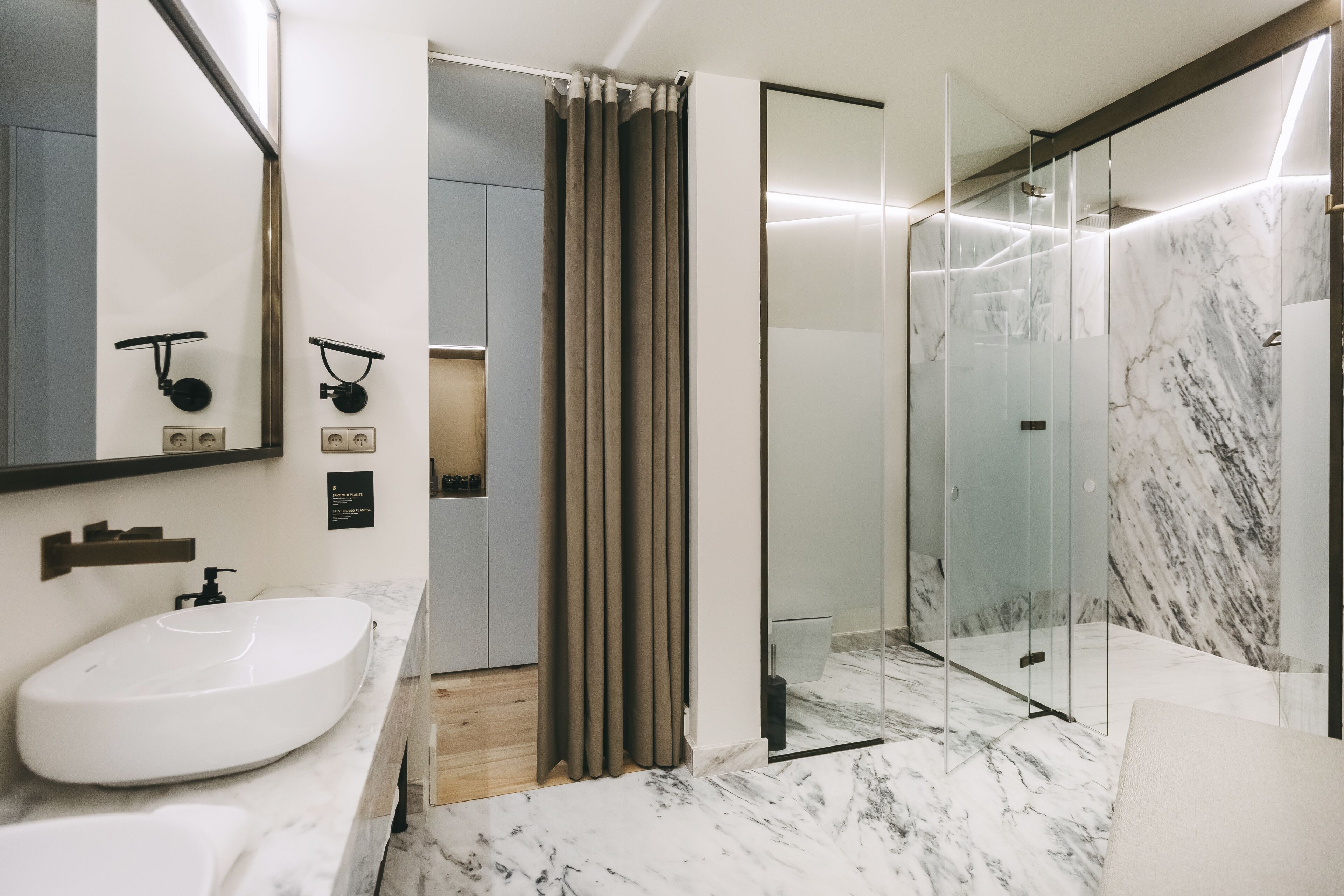 A modern bathroom with a large white sink, a glass shower enclosure, and marble flooring.