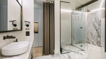 A modern bathroom with a large white sink, a glass shower enclosure, and marble flooring.