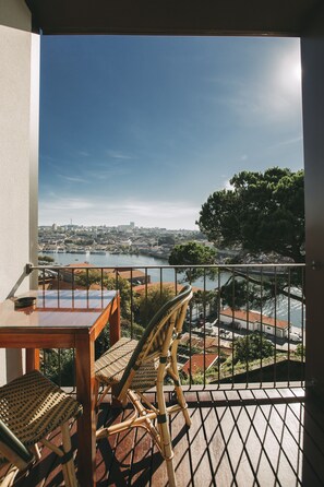 Enjoy a serene view of the river and city from this balcony, featuring a table and two chairs.