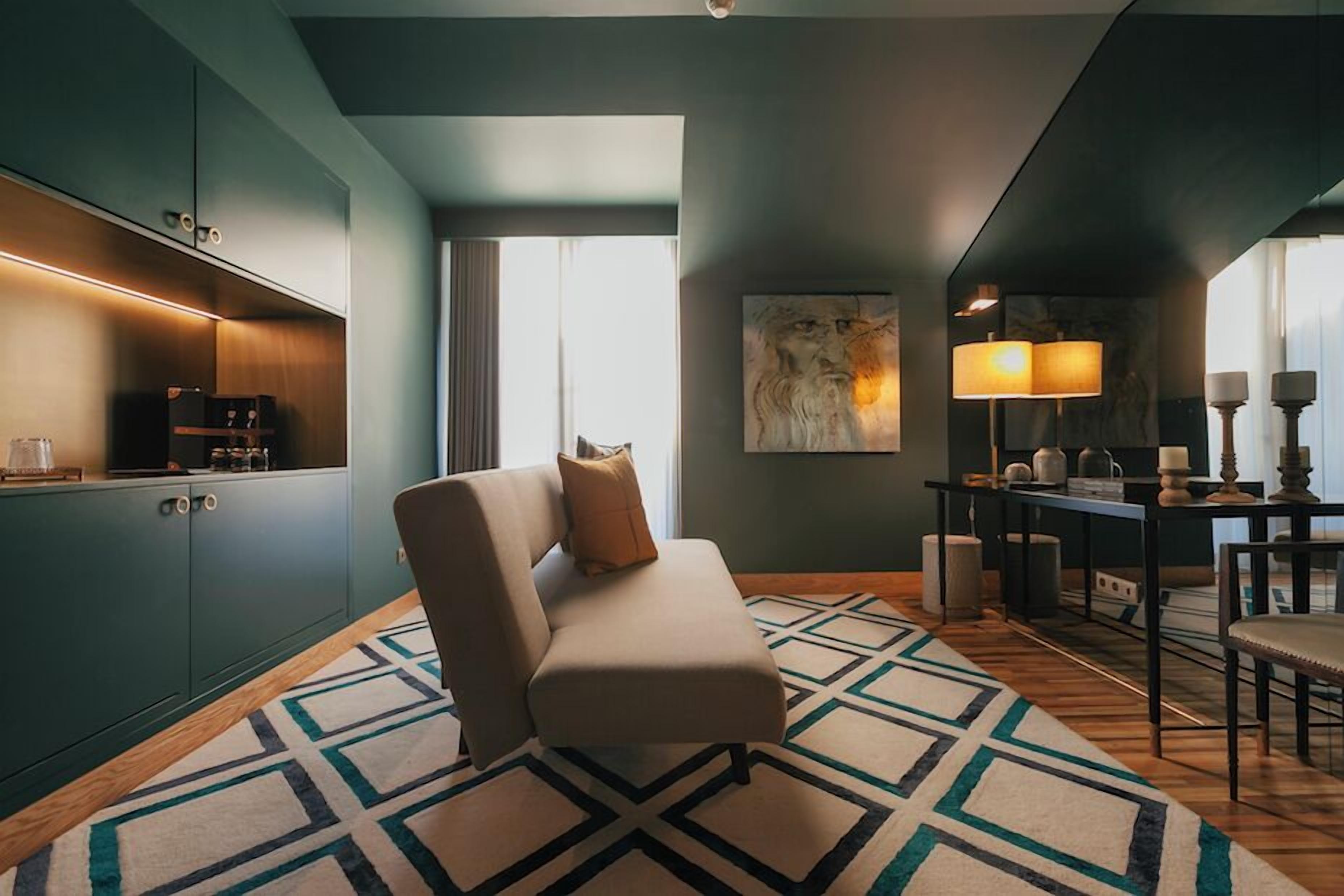 Una habitación moderna con un sofá, una mesa de comedor con sillas, una lámpara y un cuadro en la pared.