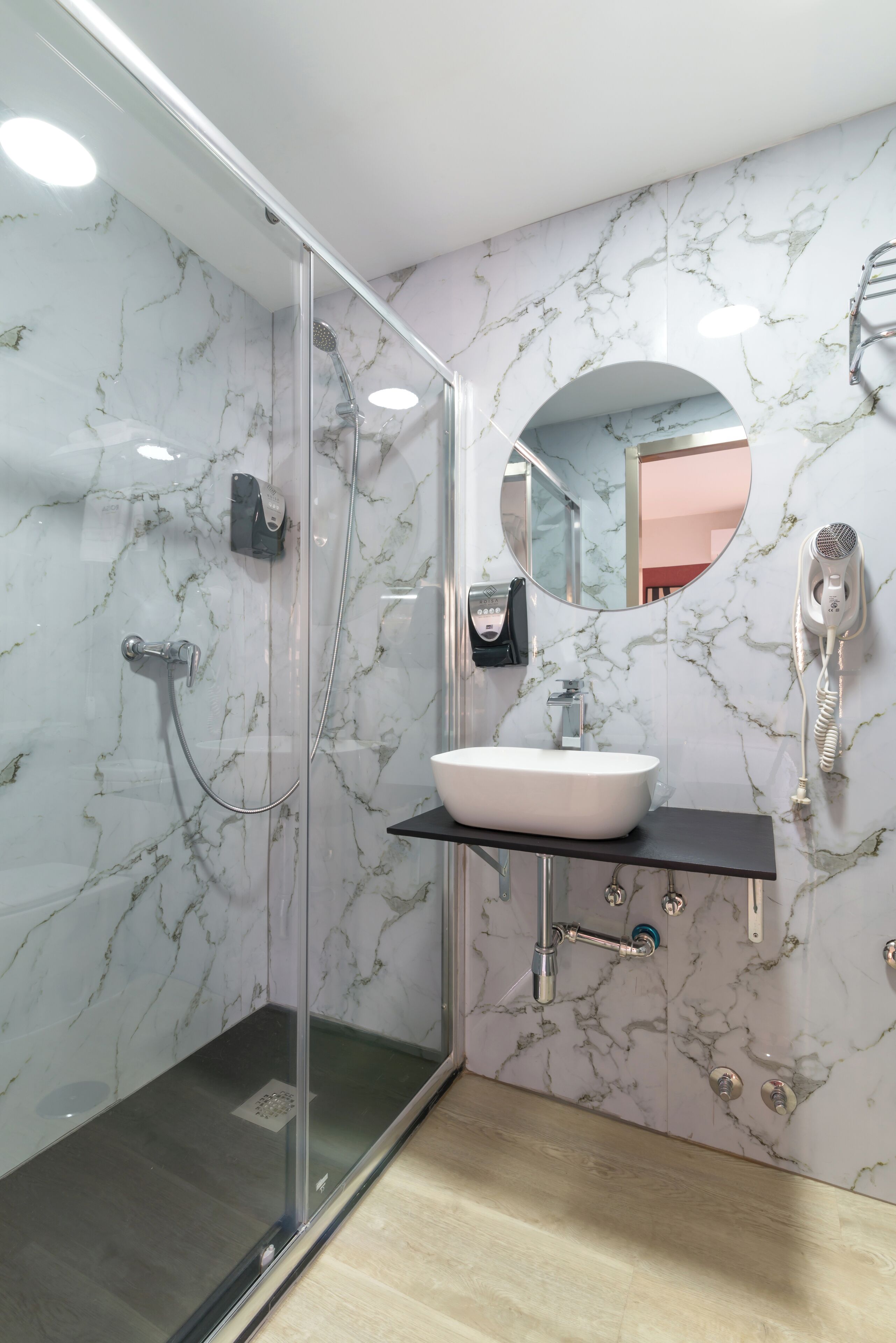 Ein modernes Badezimmer mit einer gläsernen Duschkabine, einem weißen Waschbecken und einer Marmor-Spritzschutzwand.