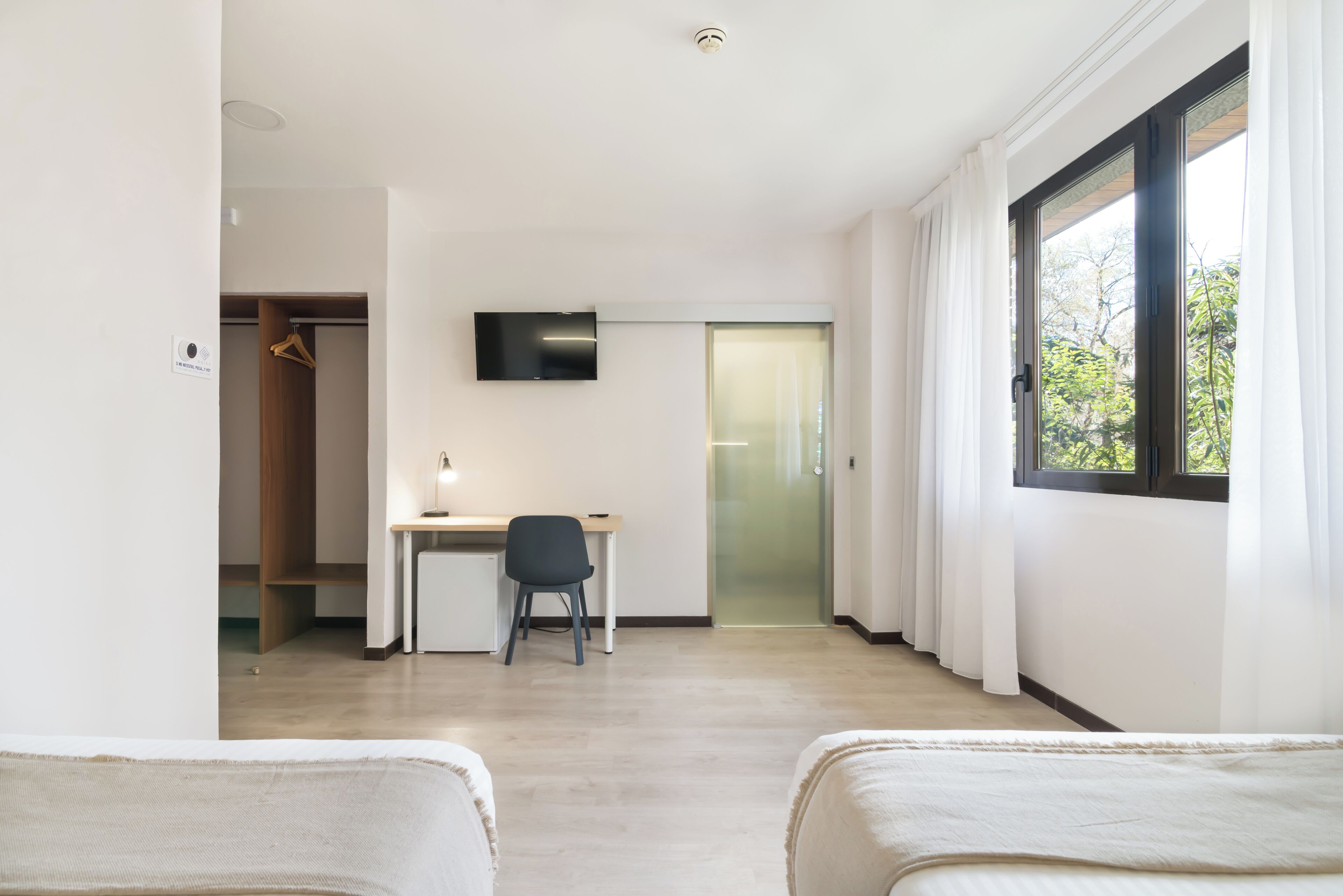 Una habitación de hotel moderna con una cama, un escritorio y un televisor.