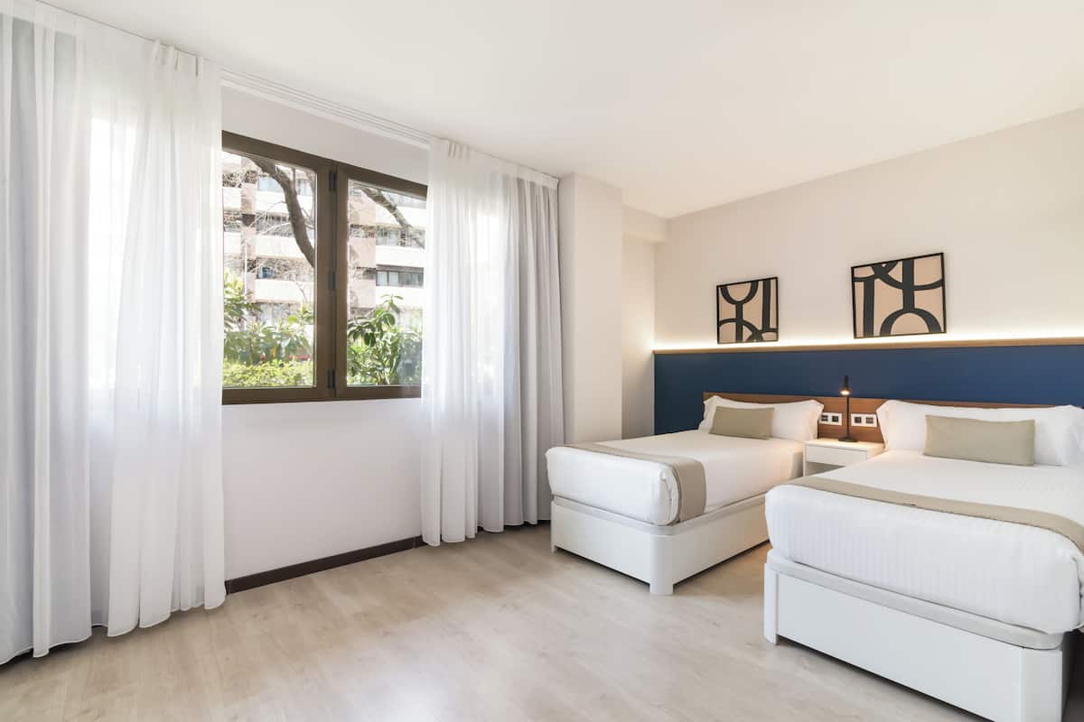 Ein Hotelzimmer mit zwei Betten, einem großen Fenster mit Vorhängen und einem Kunstwerk an der Wand.