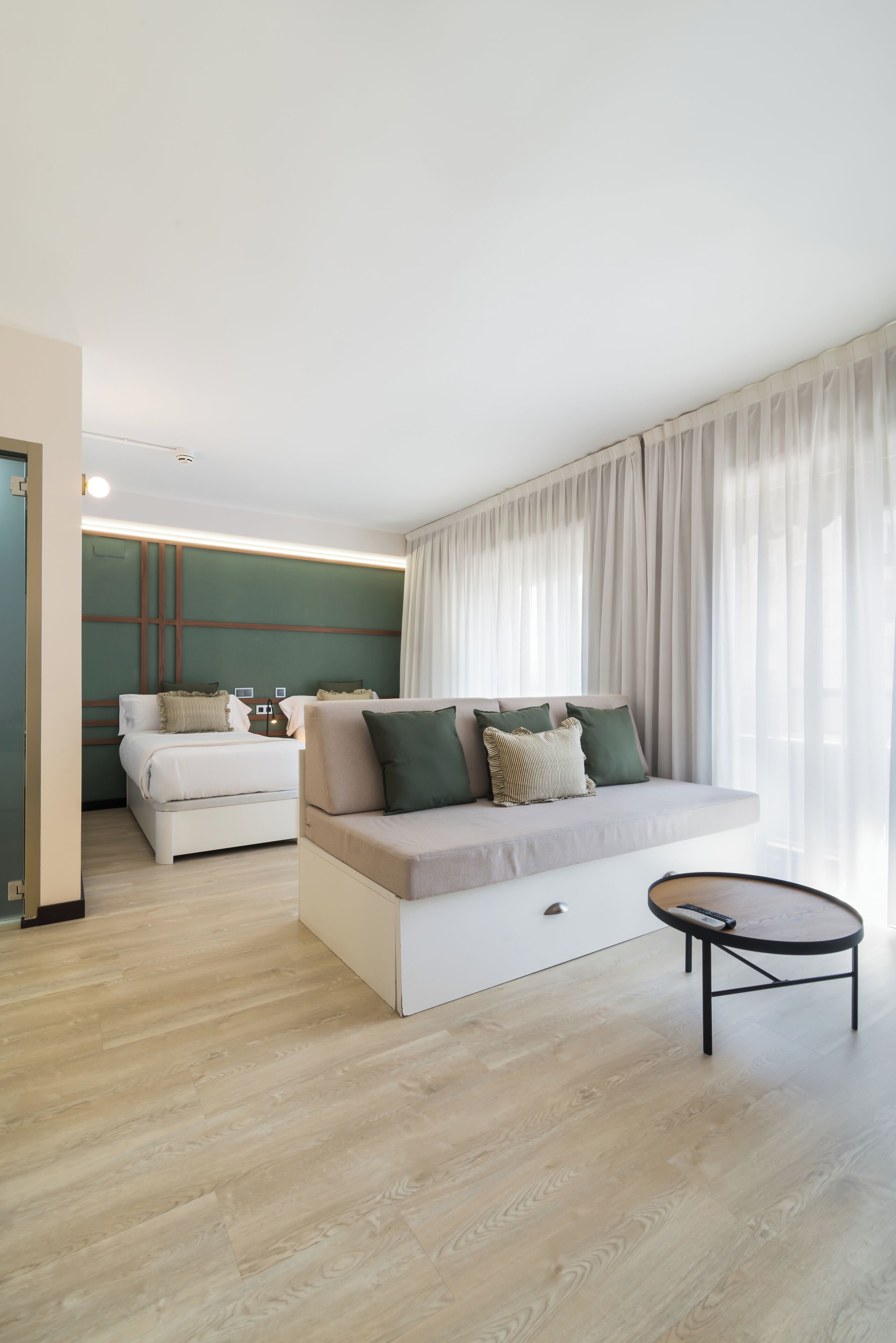 Une chambre d’hôtel moderne avec un canapé, un lit et une petite table.