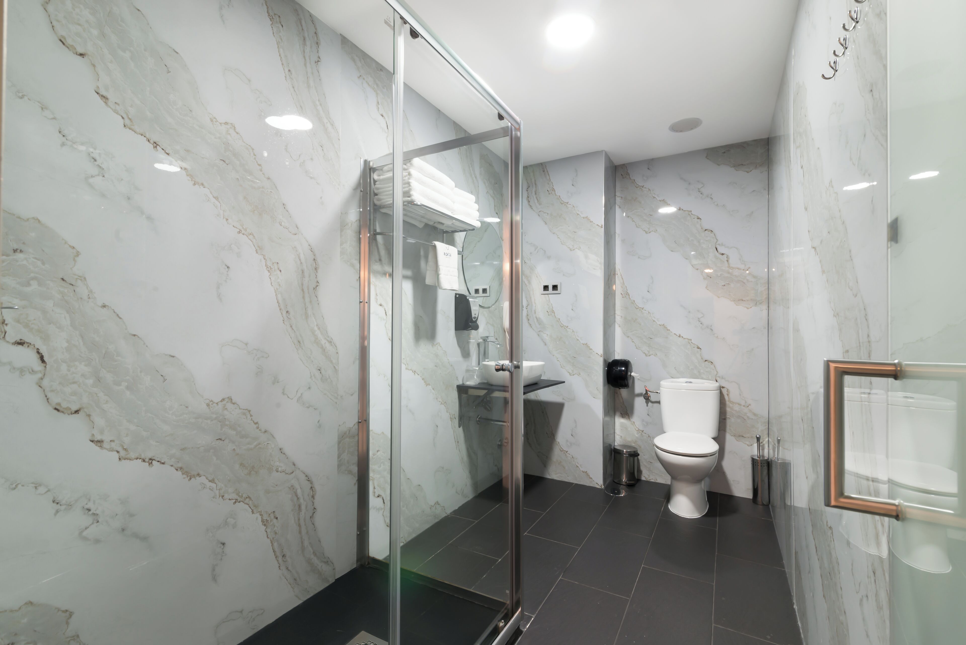 Un baño moderno con cabina de ducha de vidrio, inodoro blanco y lavabo.