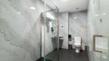 Un baño moderno con cabina de ducha de vidrio, inodoro blanco y lavabo.