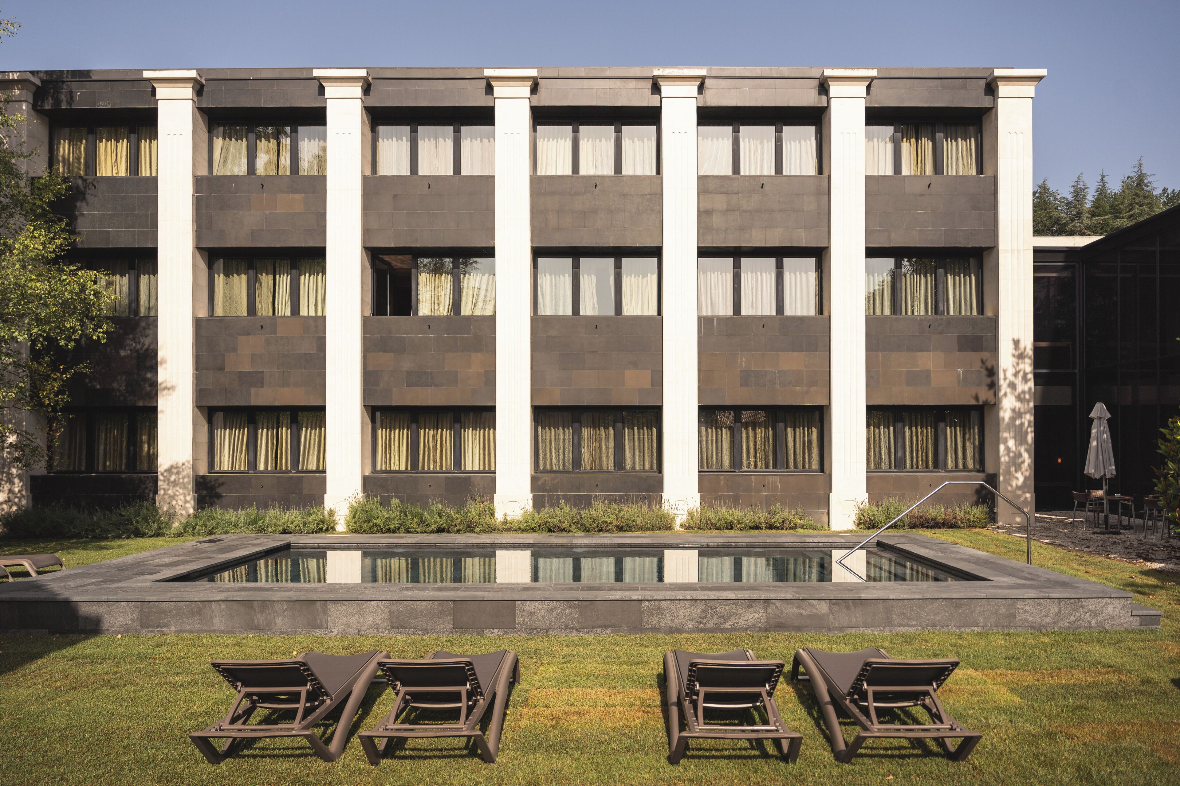 Un edifici amb piscina i gandules al davant.