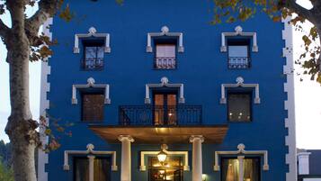 A blue building with a central entrance, multiple windows, and balconies.
