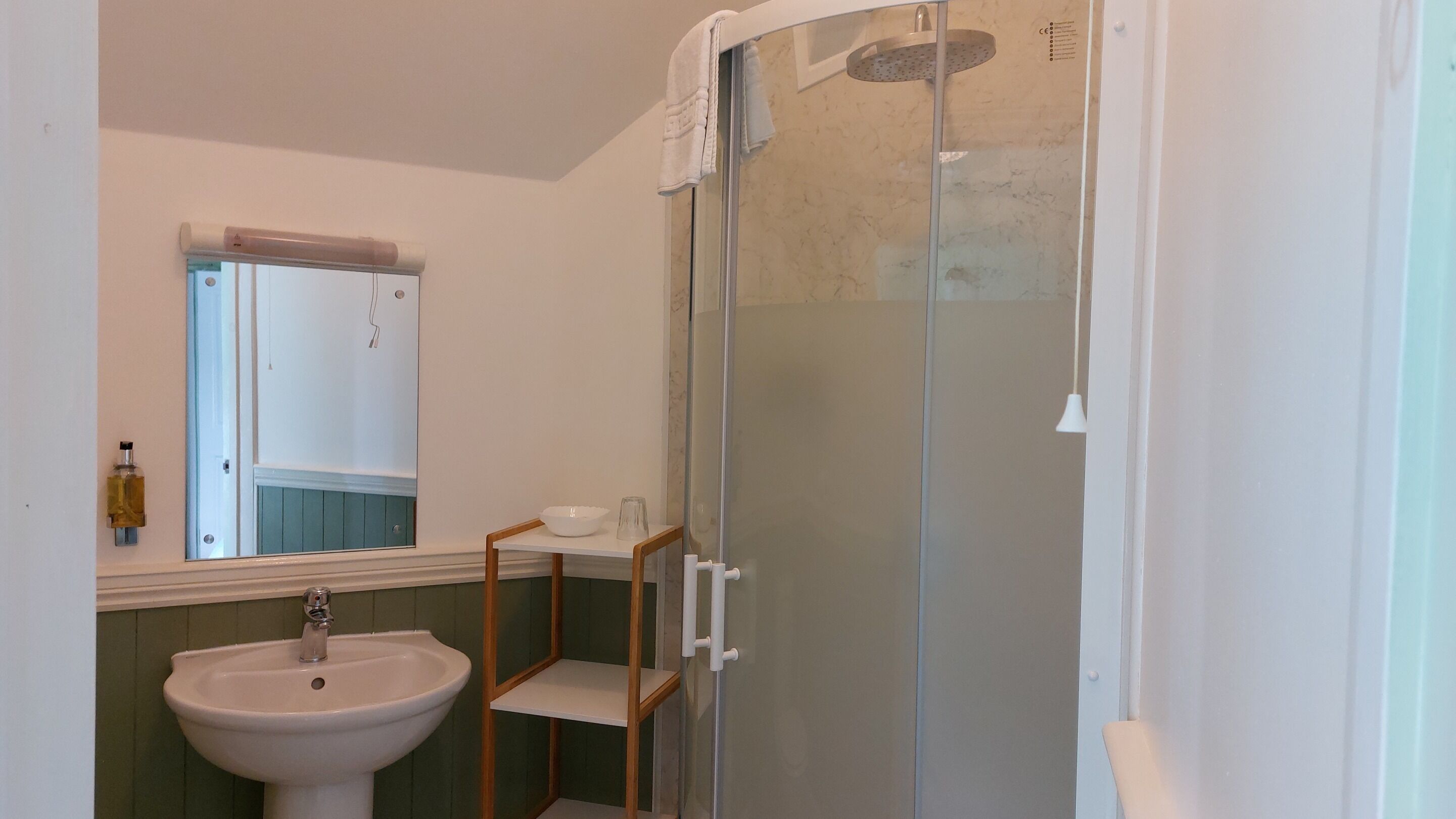 A bathroom with a glass-enclosed shower, a white sink, and a mirror above the sink.