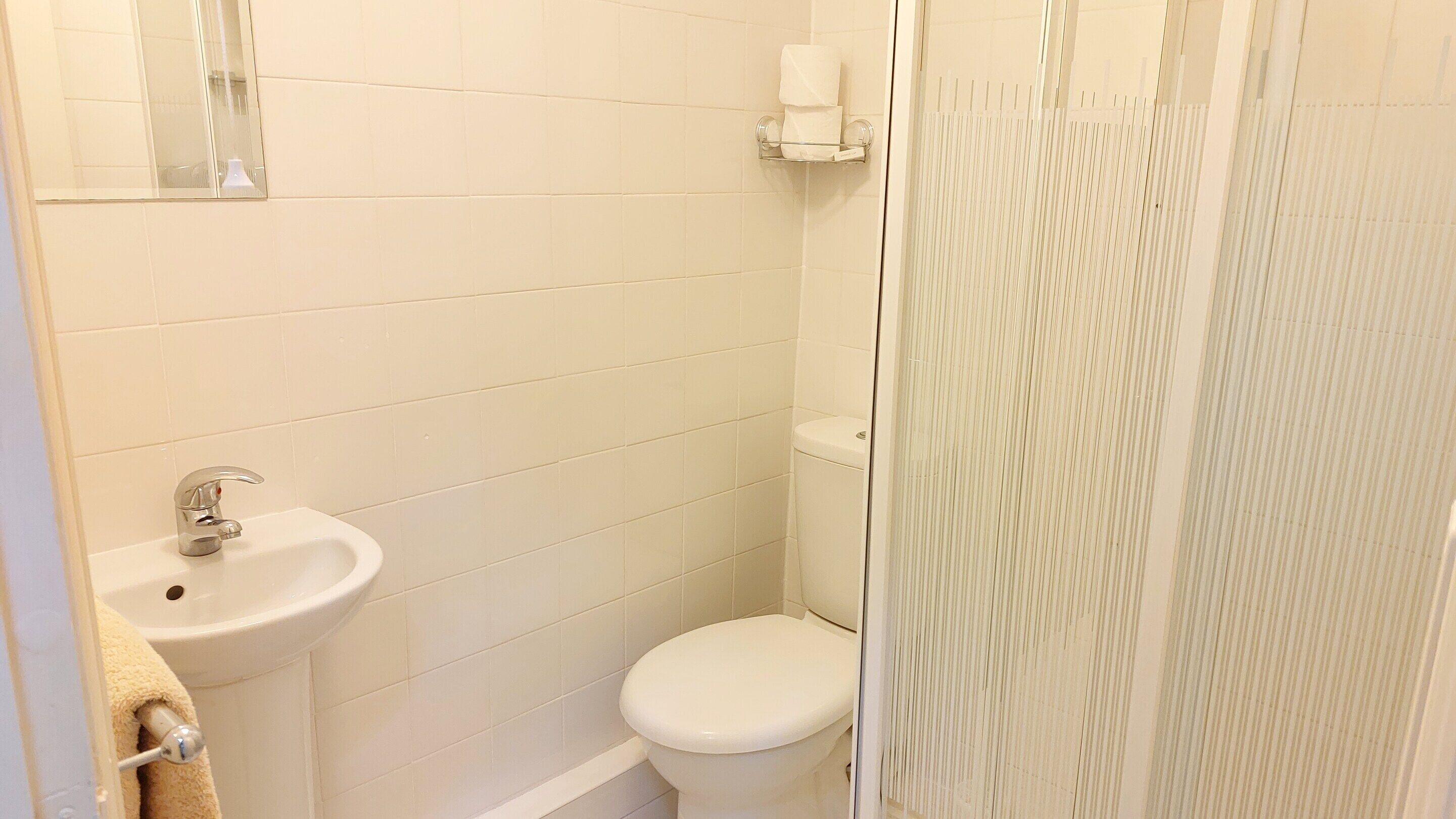 A small, clean bathroom with a sink, toilet, and a shower curtain.