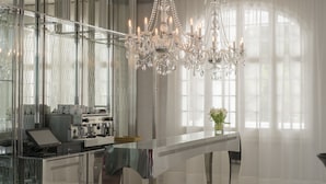 A modern interior with a glass coffee table, a coffee machine, and a chandelier. - Hotel Balneari Termes Orion (Santa Coloma de Farners)