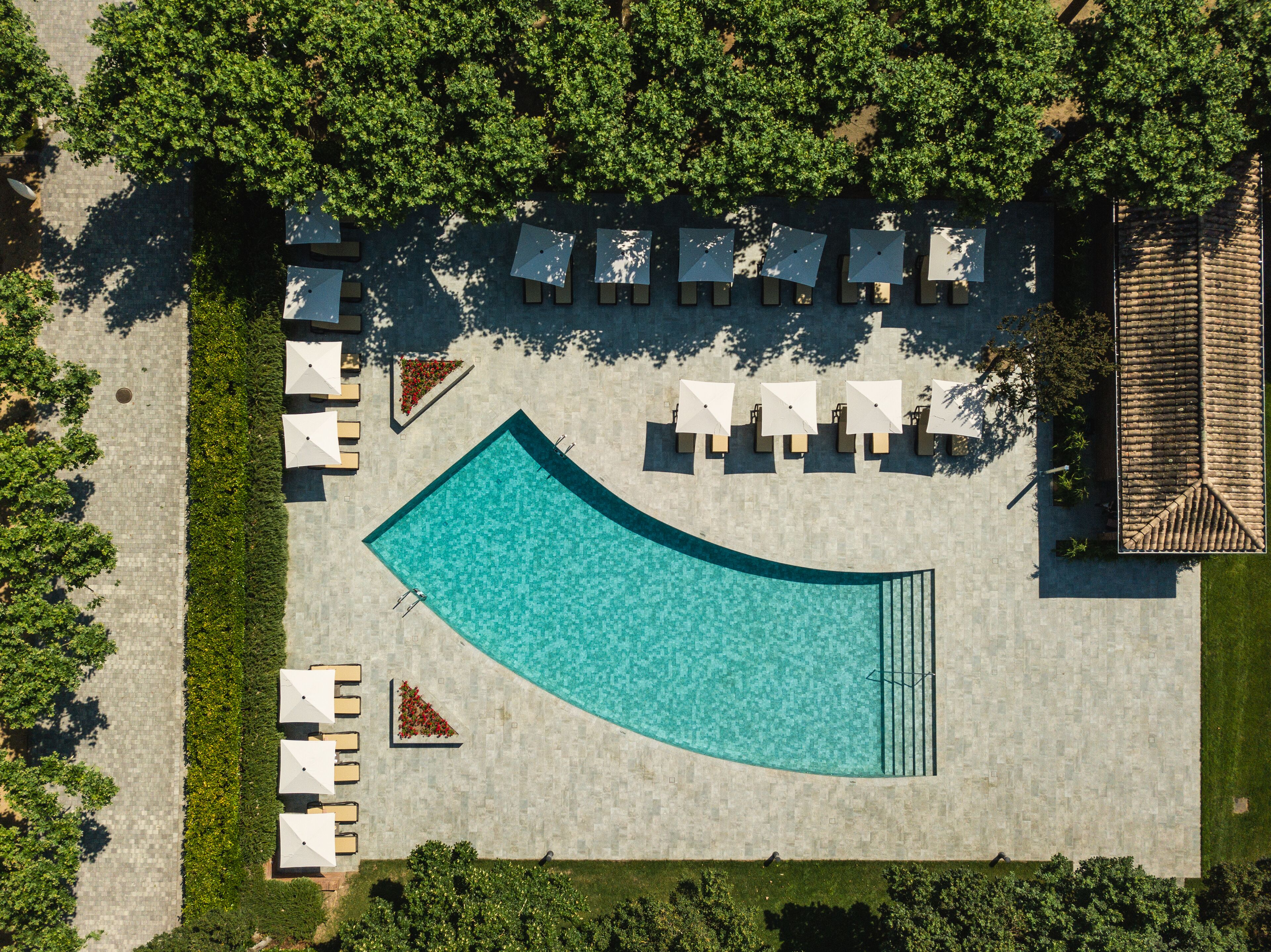 Vue aérienne d’un espace piscine avec des chaises longues et une terrasse carrelée.
