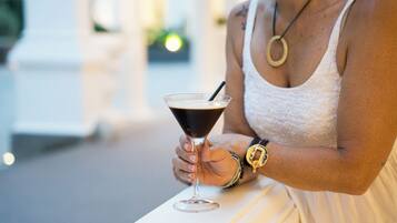 Iemand houdt een martini glas met een rietje vast.