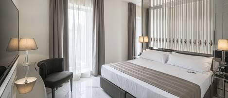 A modern hotel room with a large bed, a chair, a desk, and a mirror.