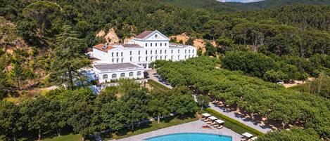 A large building with a swimming pool surrounded by trees.