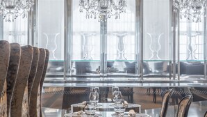 A dining area with a round table, chairs, and a chandelier. - Hotel Balneari Termes Orion (Santa Coloma de Farners)