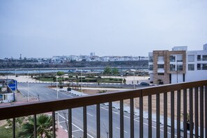 A view from a balcony overlooking a parking lot and a road leading to a cityscape.