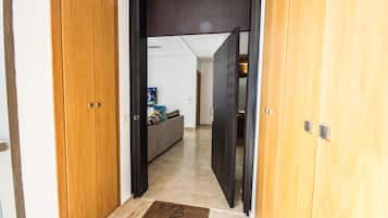 A hallway with wooden doors, a sofa with cushions, and a television in the background.