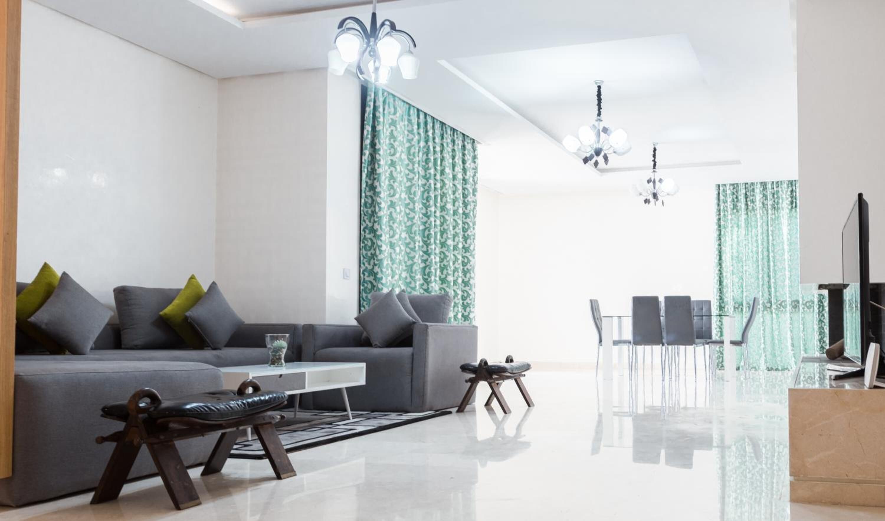 Una sala de estar moderna con un sofá gris, una mesa de centro y una zona de comedor con sillas.