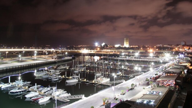 A marina at night with boats docked, a bridge in the background, and a city skyline. - Marina Rabat Suites & Apartments (Salé)