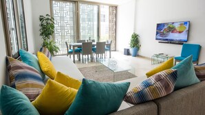 A modern living room with a sofa, TV, and dining area. - Marina Rabat Suites & Apartments (Salé)