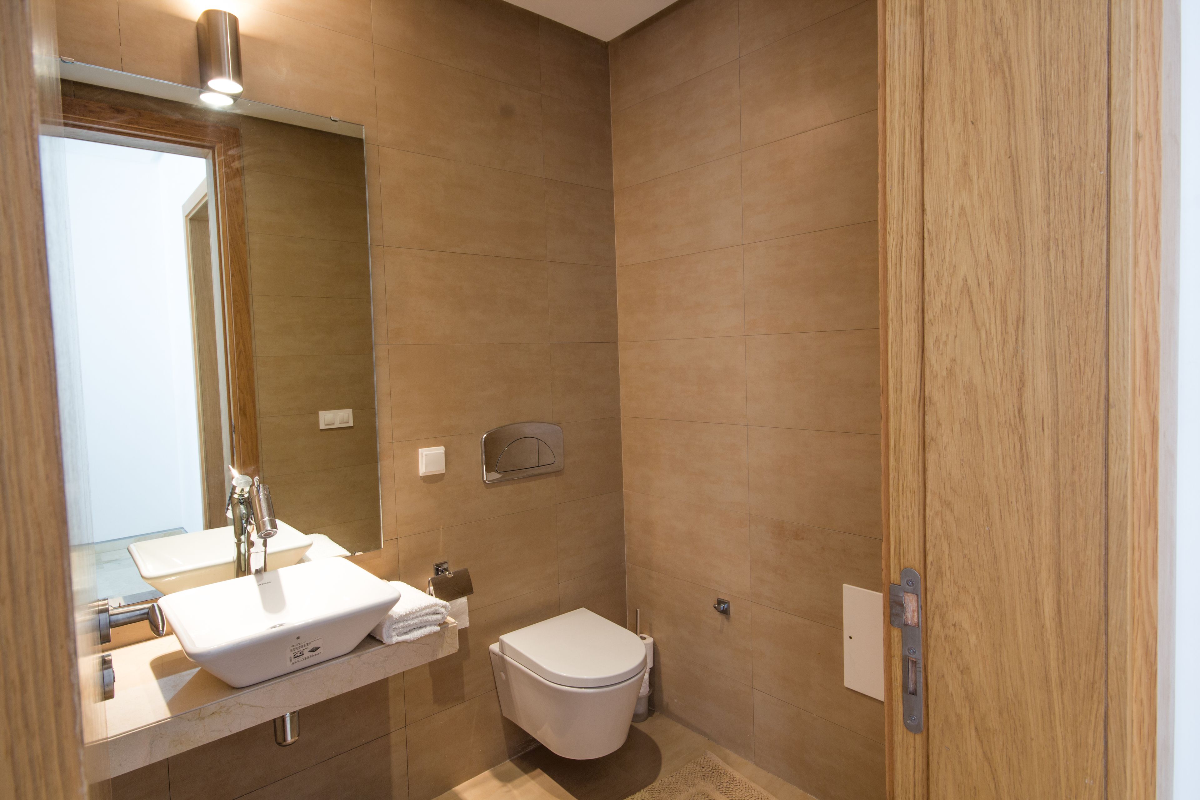 A modern bathroom with a sink, mirror, and toilet.