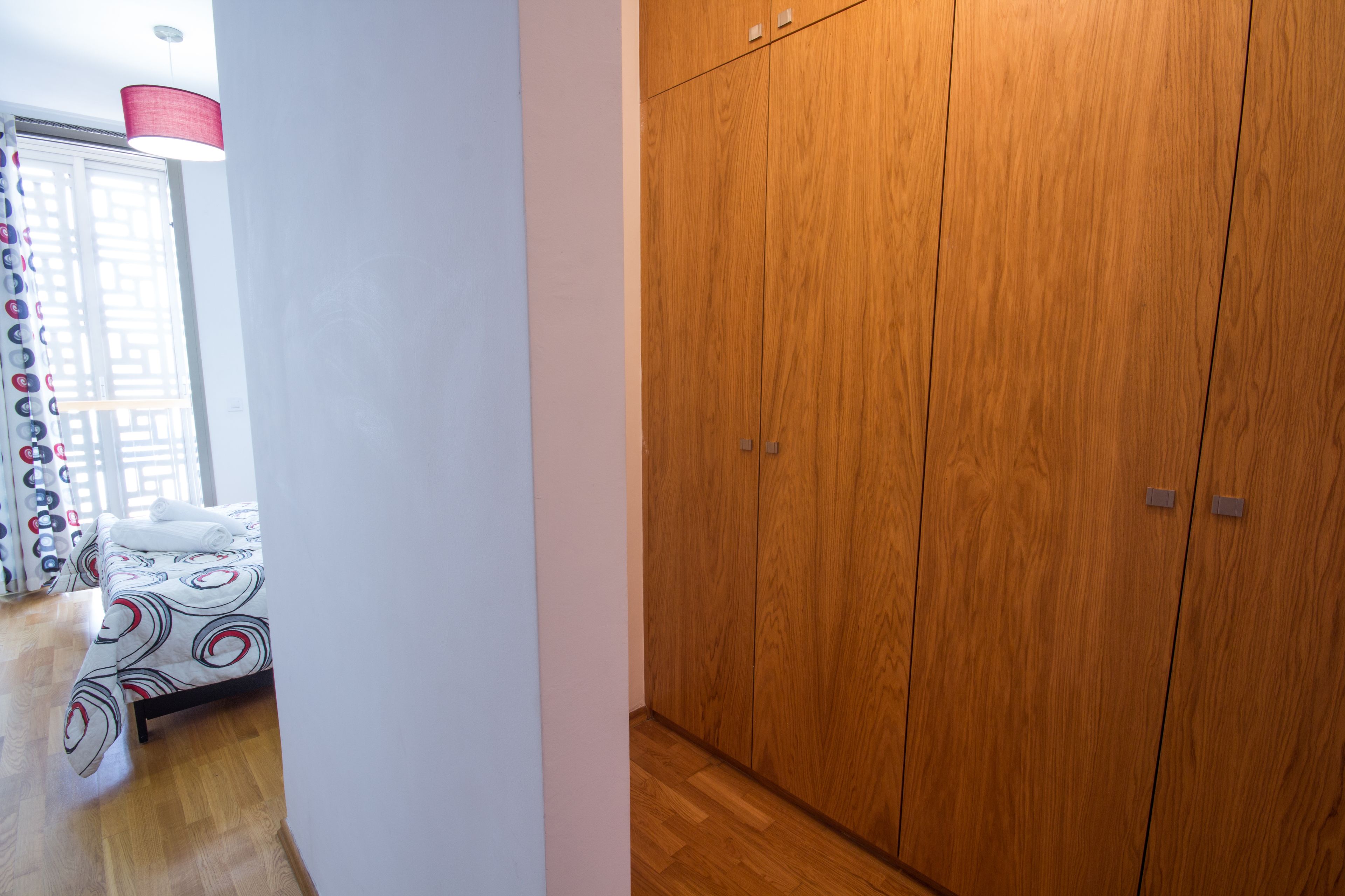 Un dormitorio con cama, armario y ventana con cortinas.
