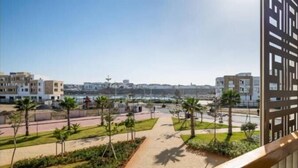 A residential area with modern buildings, a paved walkway, and palm trees. - Marina Rabat Suites & Apartments (Salé)