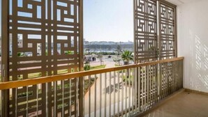 A balcony with a view of a cityscape, featuring a geometric patterned screen and a metal railing. - Marina Rabat Suites & Apartments (Salé)
