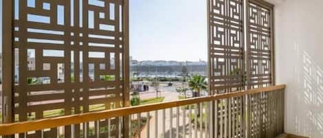 Un balcón con vista a un paisaje urbano, con un panel de diseño geométrico y barandilla de metal.