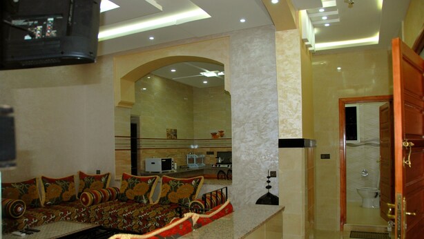 Una habitación de hotel moderna con un sofá grande, zona de comedor, cocina y baño.