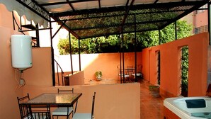 Un área de patio techada con una mesa, sillas, un jacuzzi y un calentador de agua.
