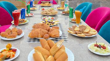 A table set with various foods and drinks, overlooking a pyramid and a desert landscape.