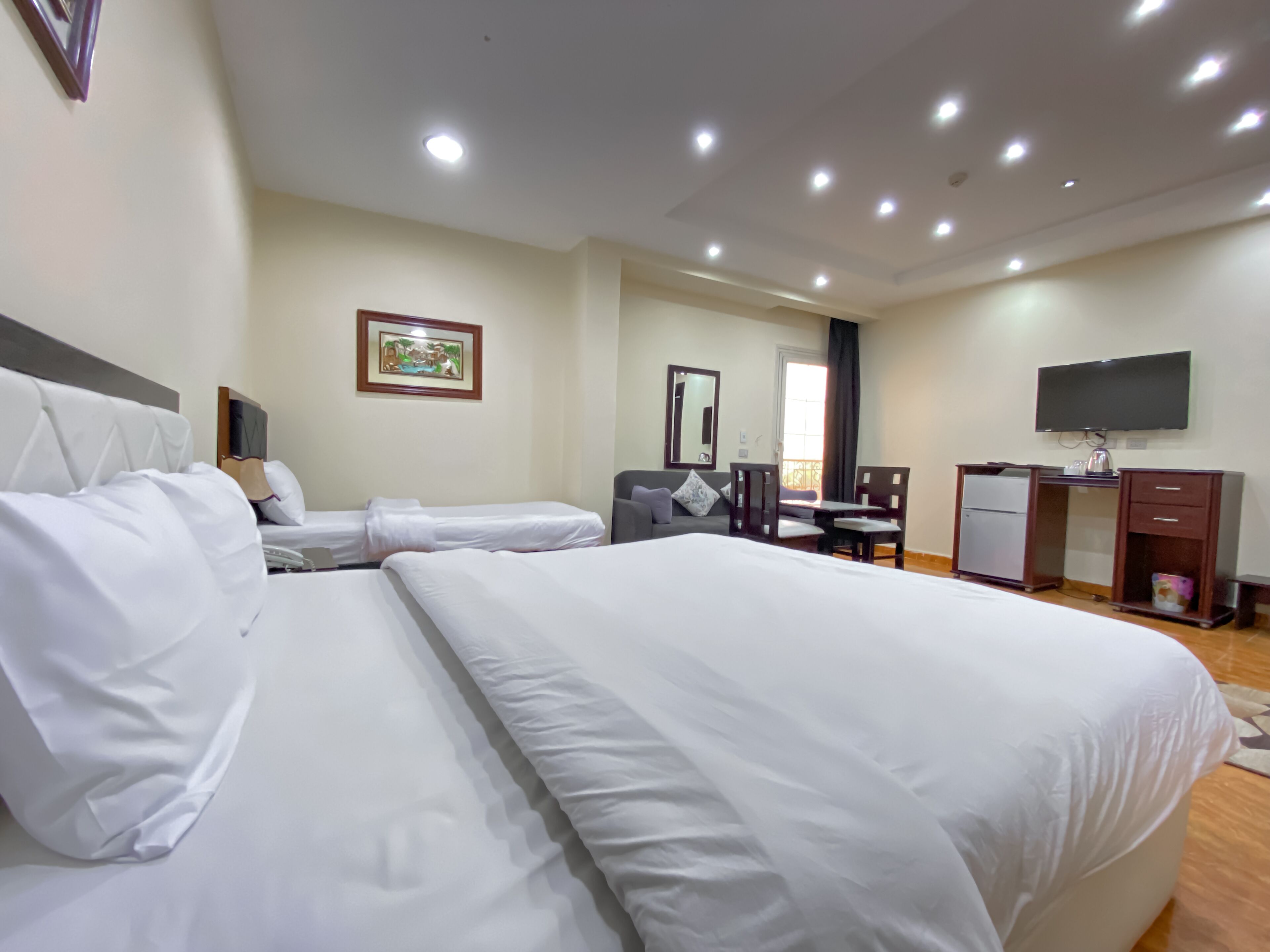 Habitación de hotel con dos camas, un escritorio, una silla, un televisor y una ventana con cortinas.