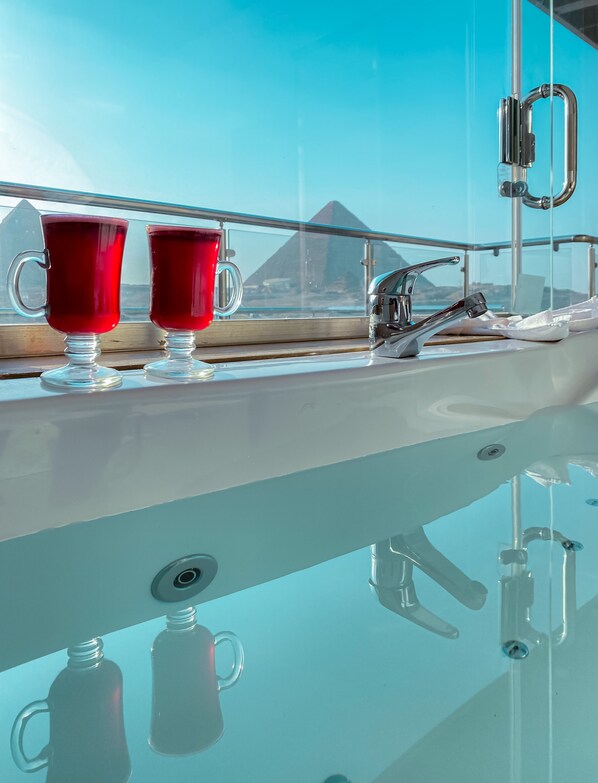 A glass table with two red cups and a faucet.
