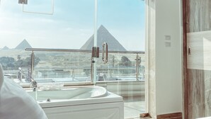 A hotel room with a large window, a sink, and a bed.