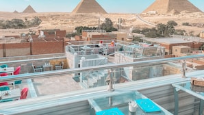 A rooftop terrace with a clear view of the pyramids in the background.