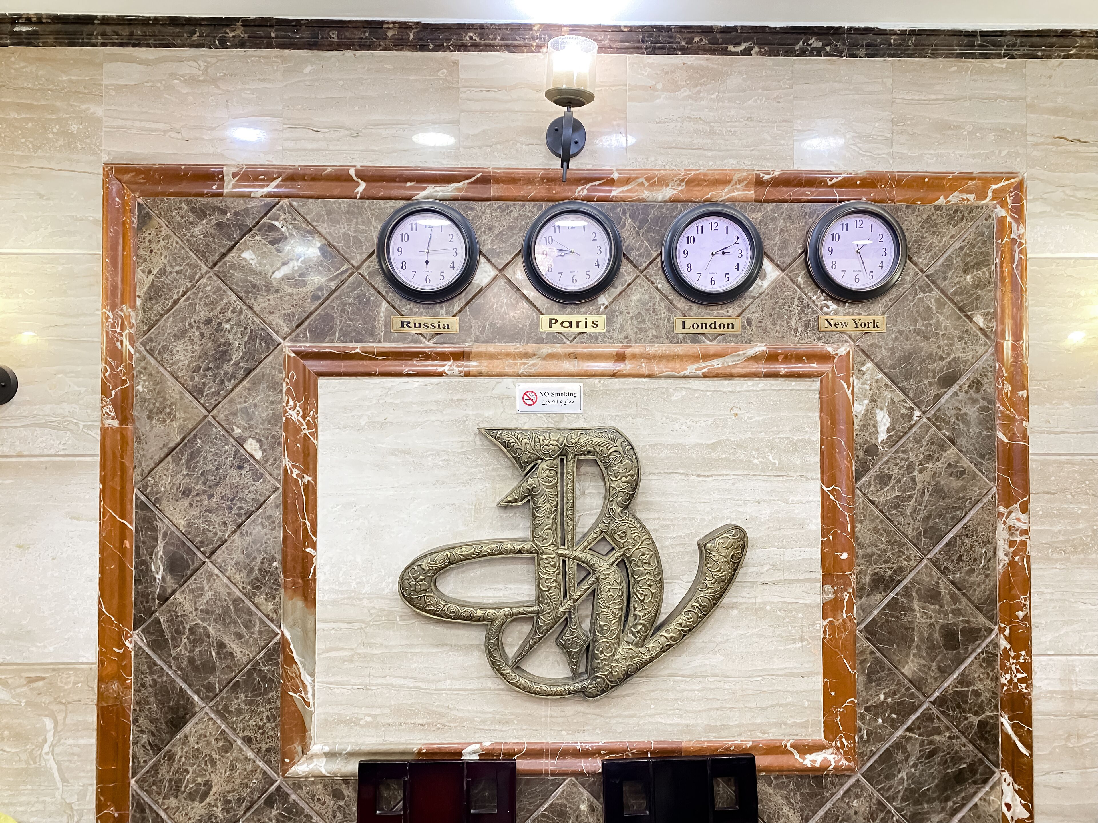 A wall with clocks labeled with city names and a large decorative letter 'B'.