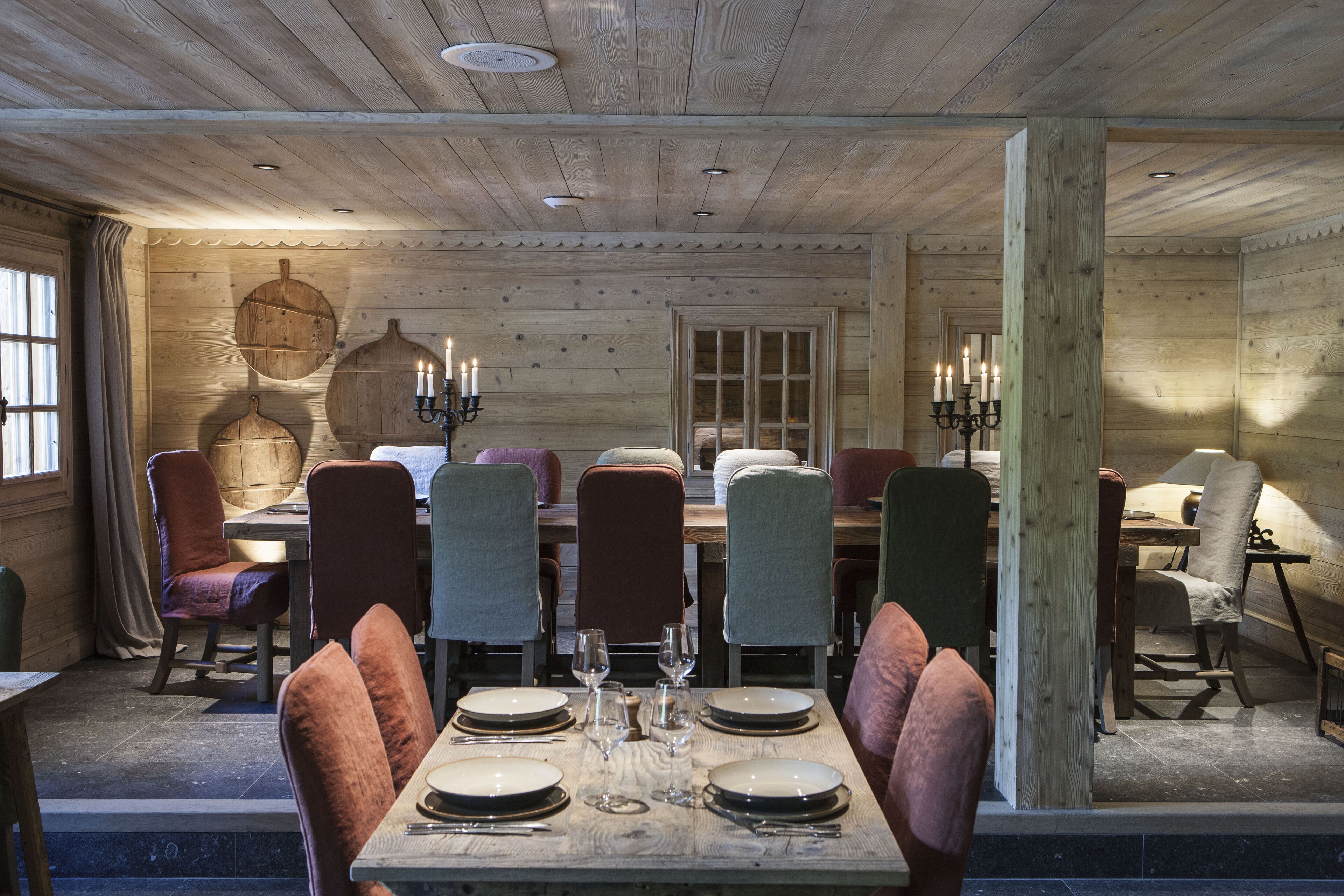 A dining area with a wooden table set for six, surrounded by chairs with cushioned seats.