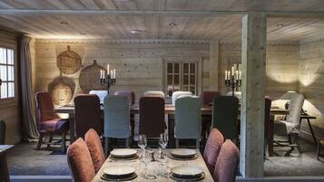 A dining area with a wooden table set for six, surrounded by chairs with cushioned seats.