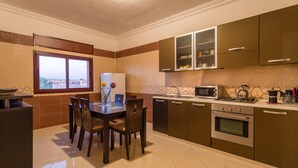 Una cocina moderna con comedor, que incluye un ventanal grande, un refrigerador, un microondas, un horno y una cafetera.