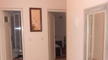 A hallway with a chandelier, a framed picture on the wall, and doors leading to other rooms.