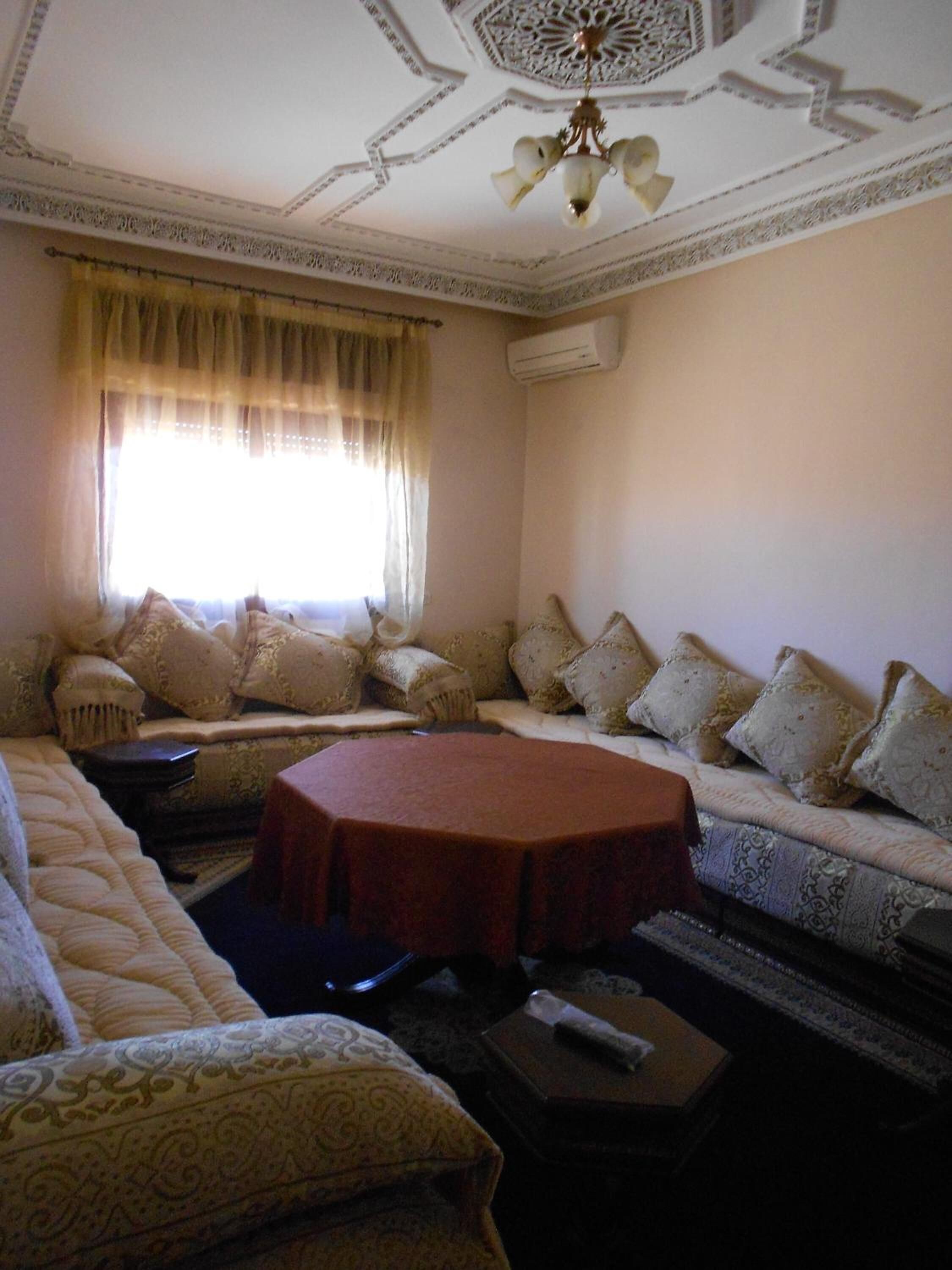 A room with a sofa set, a round table, and a patterned rug.