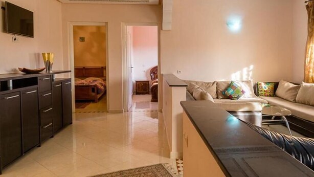 Una sala de estar con sofá, mesa de centro y televisor montado en la pared.