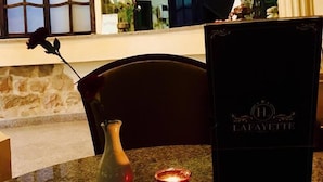 Zona de recepción de hotel con mostrador de mármol, un jarrón con una sola flor, una vela encendida y un letrero negro con el nombre del hotel.